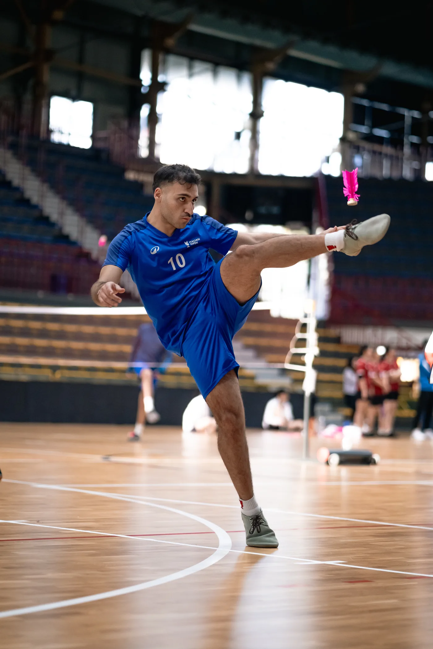 Atleta italiano colpisce il volano rosa durante una gara internazionale