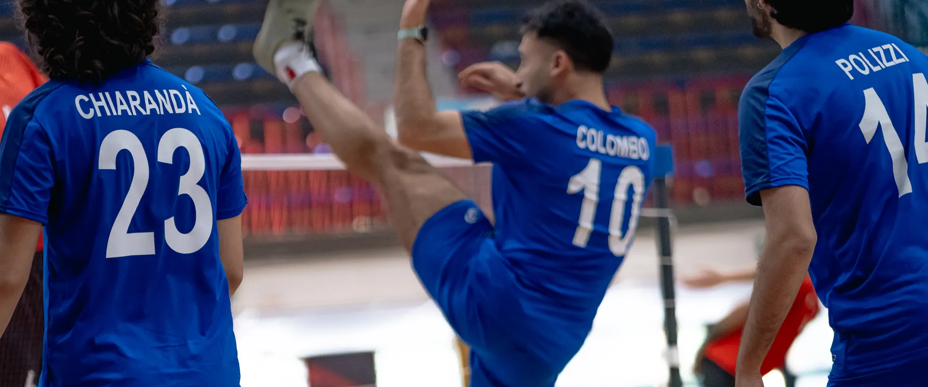 Un atleta azzurro colpisce il volano fra i compagni di squadra a bordo campo